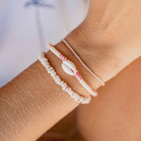 Close-up of a wrist wearing two beaded bracelets with a blurred background